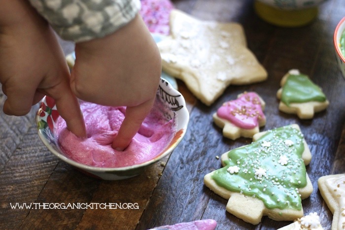 Chicldren dipping their fingers into a bowl of icing for Traditional Rolled Sugar Cookies with a New Twist