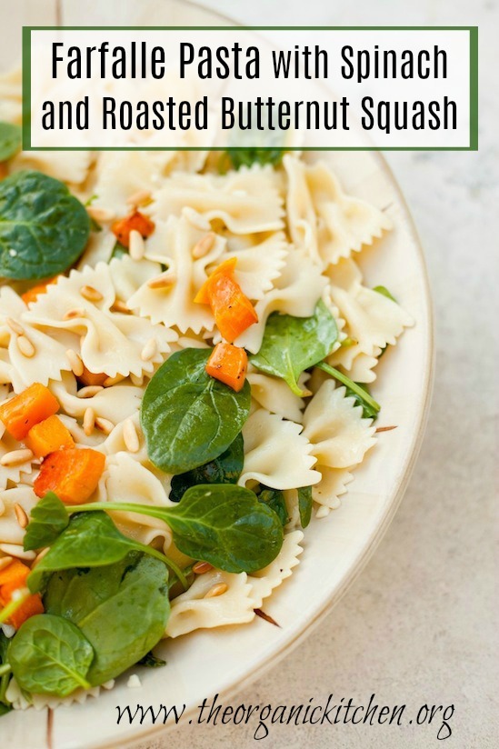Farfalle Pasta with Roasted Butternut Squash and spinach in a large beige bowl on marble surface
