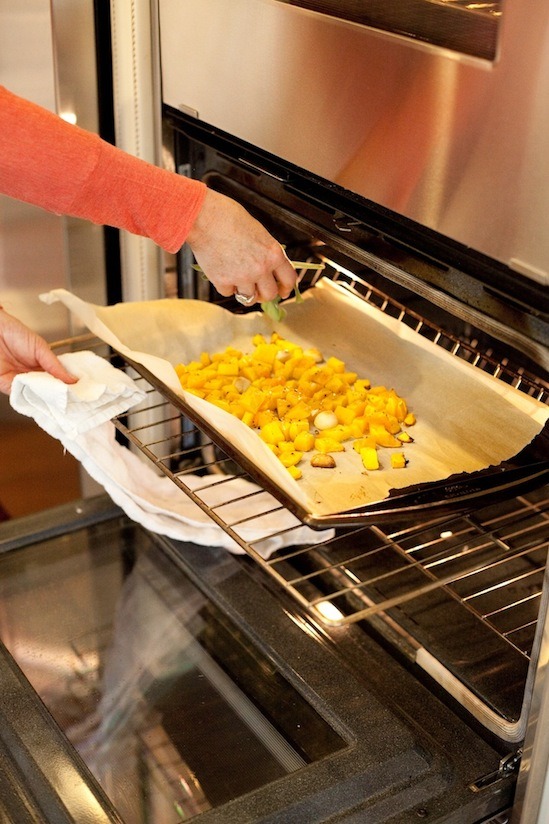 A pan of cut butternut squash on rimmed baking sheet being put in the over to roast for Farfalle Pasta with Roasted Butternut Squash from www.theorganickitchen.org