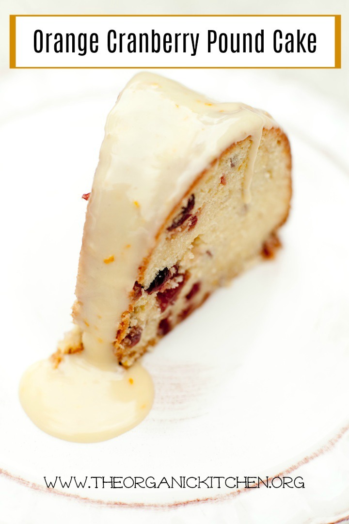 A slice of Orange Cranberry Pound Cake drizzled with orange glaze on white plate