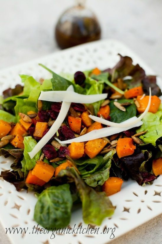 How to Make Delicious Salad Dressings at Home-Plus Recipes! A white plate filled with green salad and roasted butternut squash with bottle of salad dressing in the background