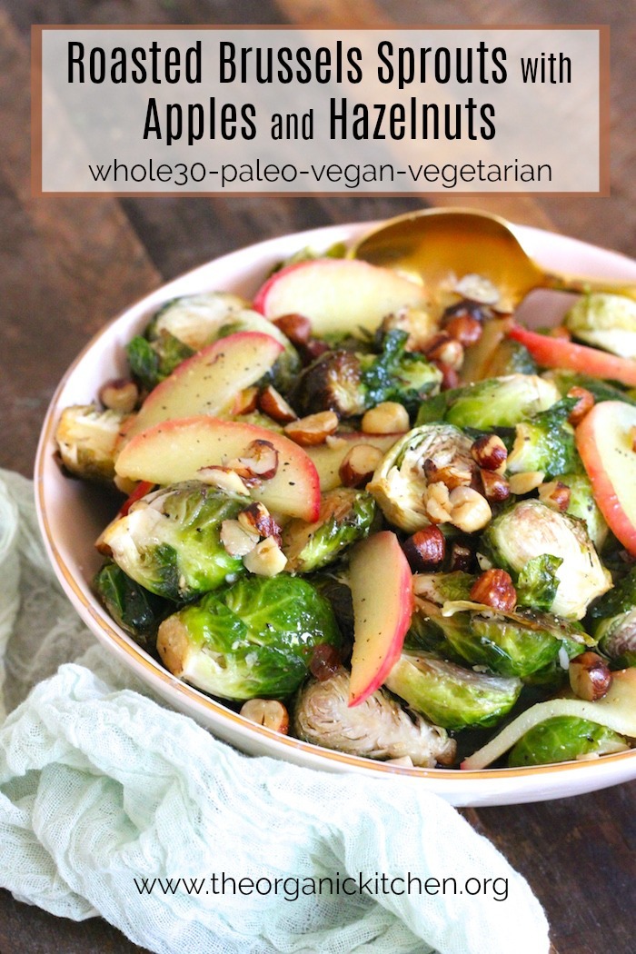 Roasted Brussels Sprouts with Apples and Hazelnuts in a peach colored bowl on wooden table