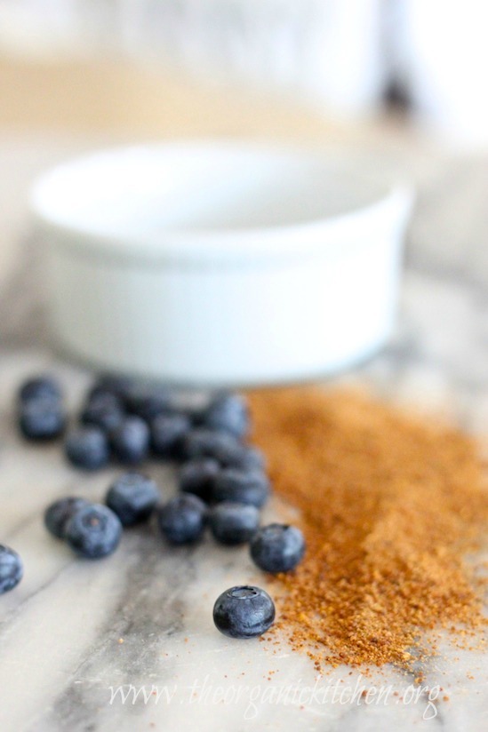 A white ramekin with blueberries and coconut sugar on marble table. Heavenly Blueberry Bread Pudding 