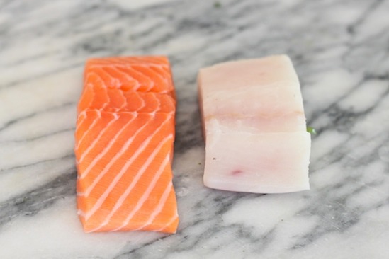 Raw salmon and halibut on marble surface in preparation for making Fresh Fish Tacos 