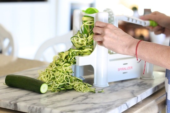 A woman's demonstrating how to make zoodles for Almond Pesto Zucchini Noodles 