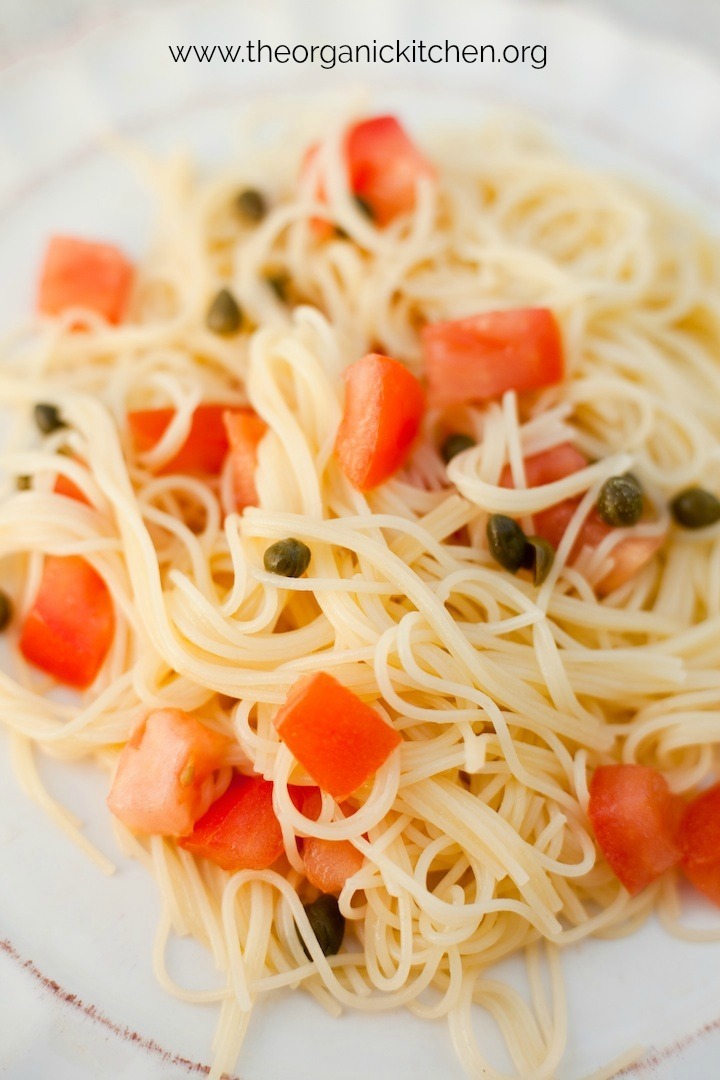 Pasta with Tomatoes and Lemon garnished with capers on white dish