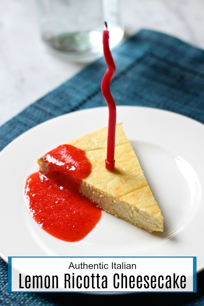 A piece of Lemon Ricotta Cheesecake with a red birthday candle on a white plate set on a blue place mat