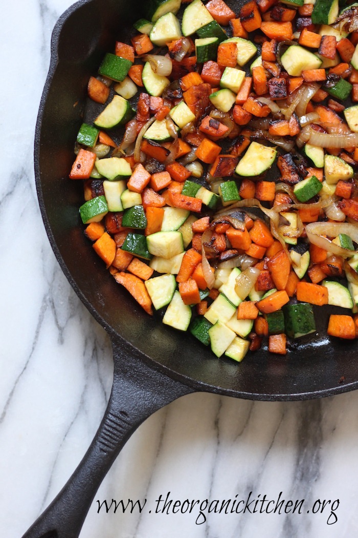 Breakfast Hash with Poached Eggs in a large cast iron skillet on marble surface