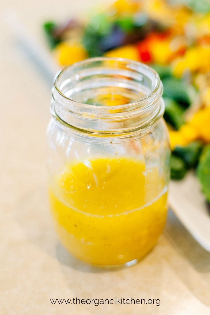 A mason jar with brightly colored citrus salad dressing for use on Kale Salad with Citrus Vinaigrette #kalesalad #citrusvinaigrette #wintersalad