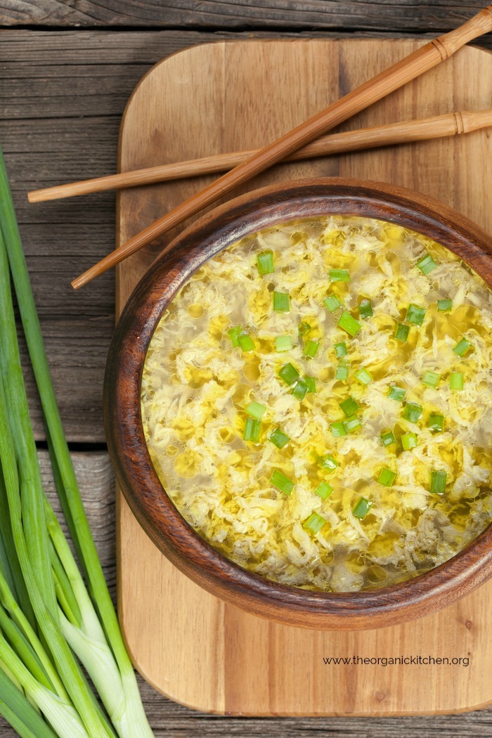 Egg drop Soup in a wooden bowl and a wooden cutting board