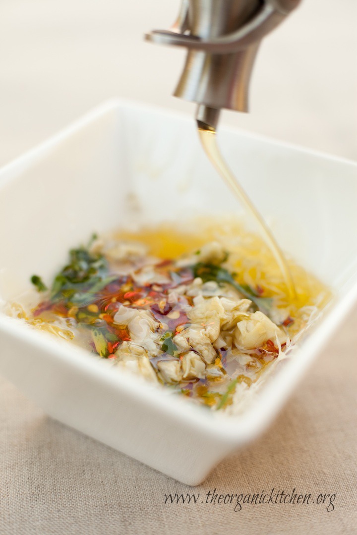 Olive oil being drizzled into a bowl of Parmesan Artichoke Heart Dipping Oil