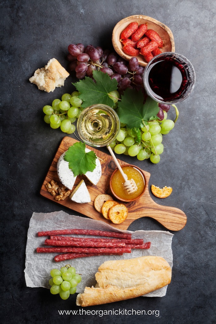 Charcuterie board with honey and grapes on black background