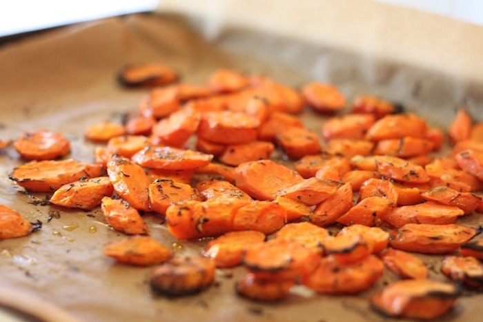 Roasted carrots on parchment covered cookie sheet for use in Baby Spinach Salad with Roasted Carrots and Israeli Couscous