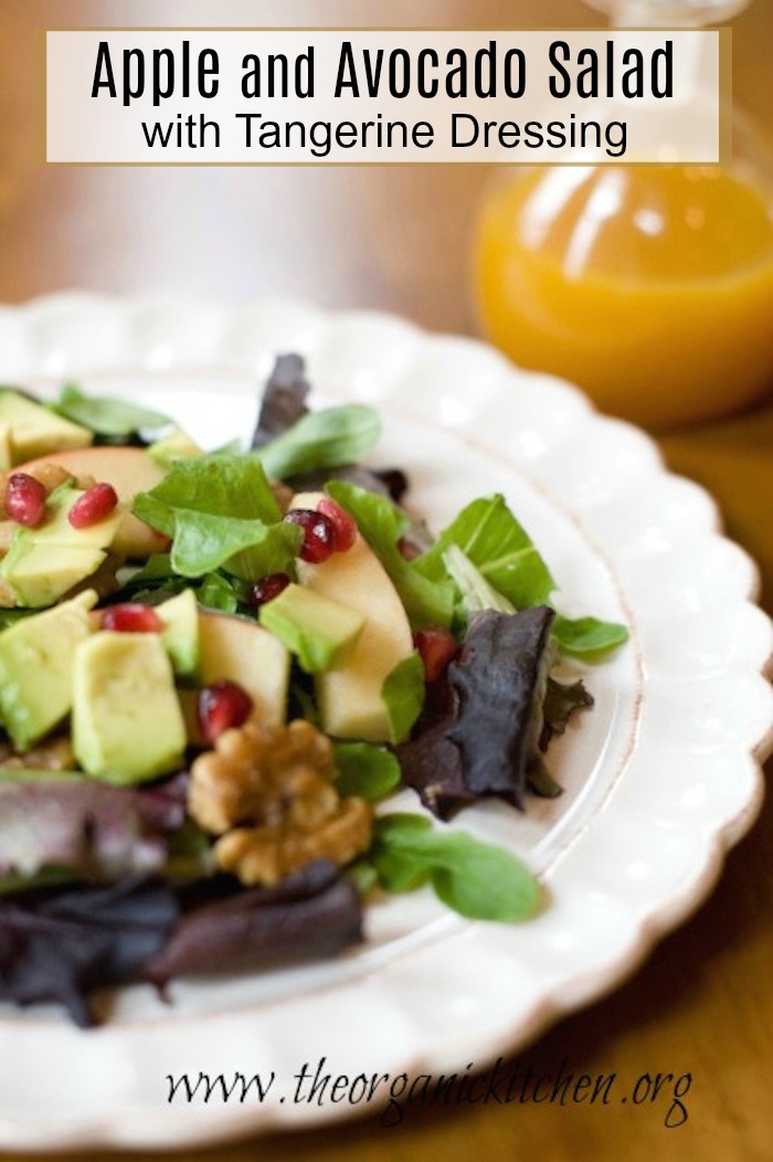 Apple and Avocado Salad with Tangerine Dressing on white plate set on wood table with a bottle of dressing in the background