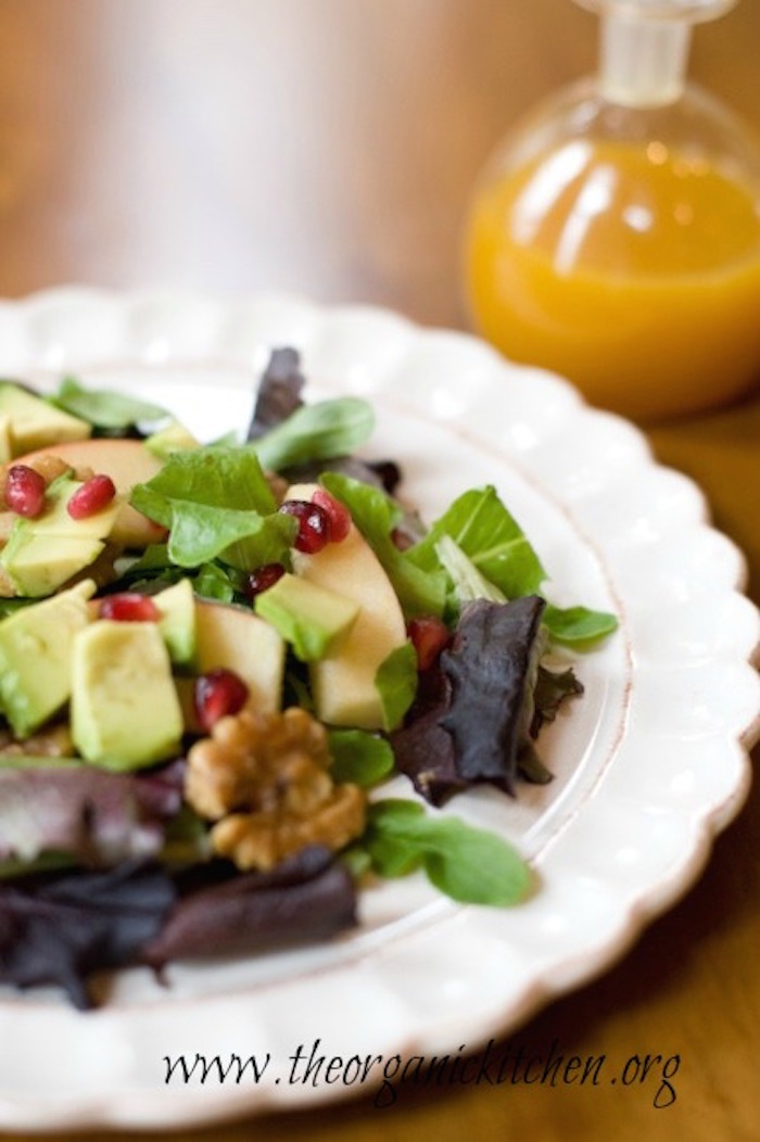 Apple and Avocado Salad with Tangerine Dressing on white plate with bottle of dressing in background