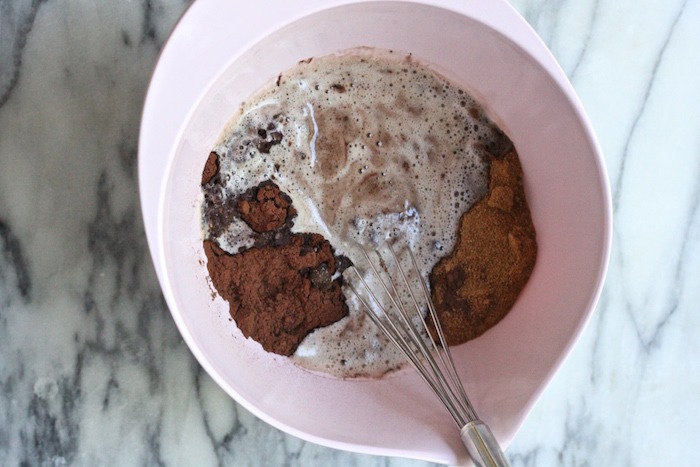 The ingredients for Brown Butter Brownies with Macadamia Nuts in a pink mixing bowl with whisk