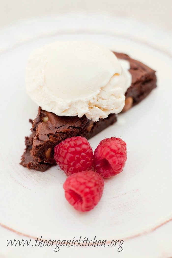 Browned Butter Brownies with Macadamia Nuts Browned Butter Brownies with Macadamia Nuts topped with ice cream and raspberries on white plate