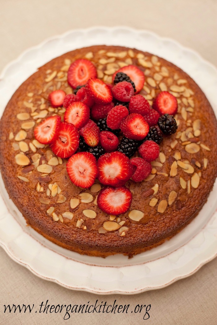 Traditional Olive Oil Cake topped with fresh berries on white plate