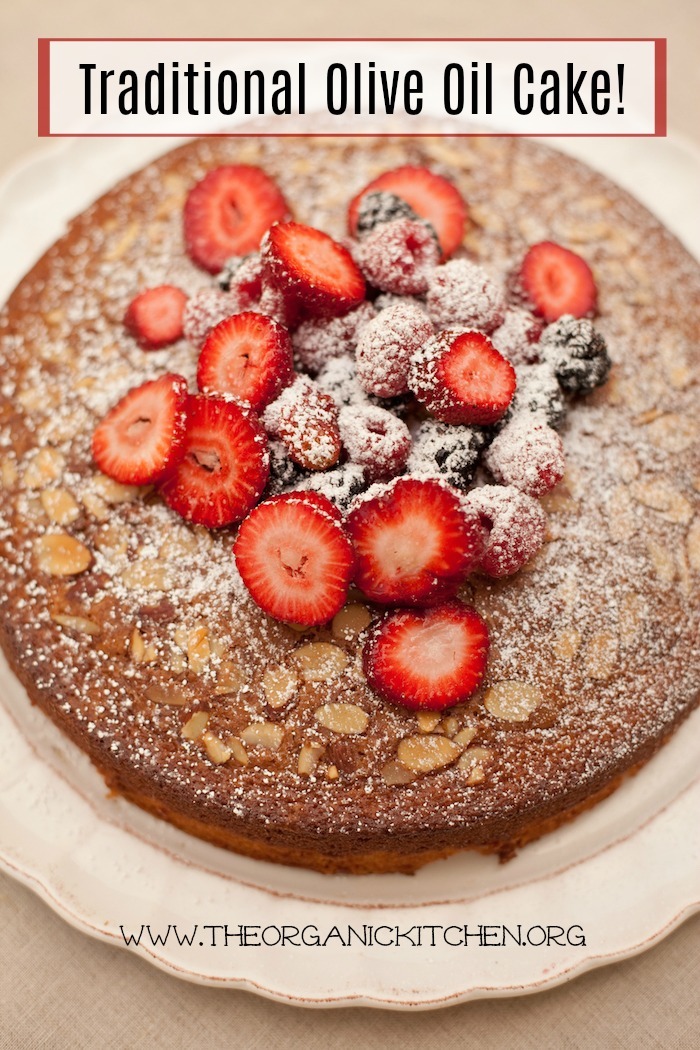 Traditional Olive Oil Cake topped with berries and dusted with powdered sugar on white