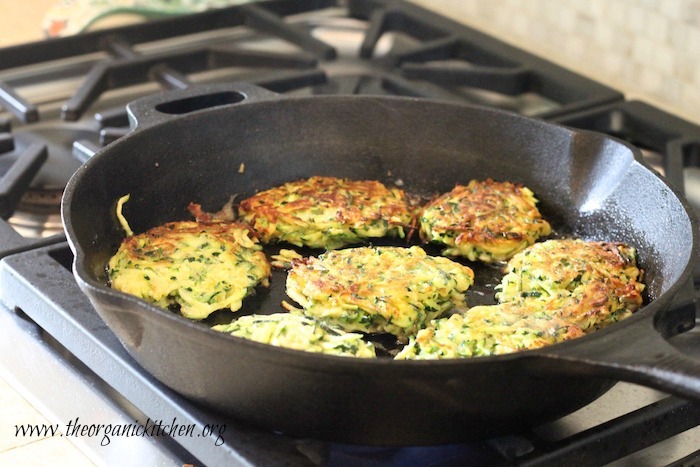 Zucchini Fritters with Lemon Ricotta (with Gluten Free Option) cooking in a cast iron skillet on the stovetop