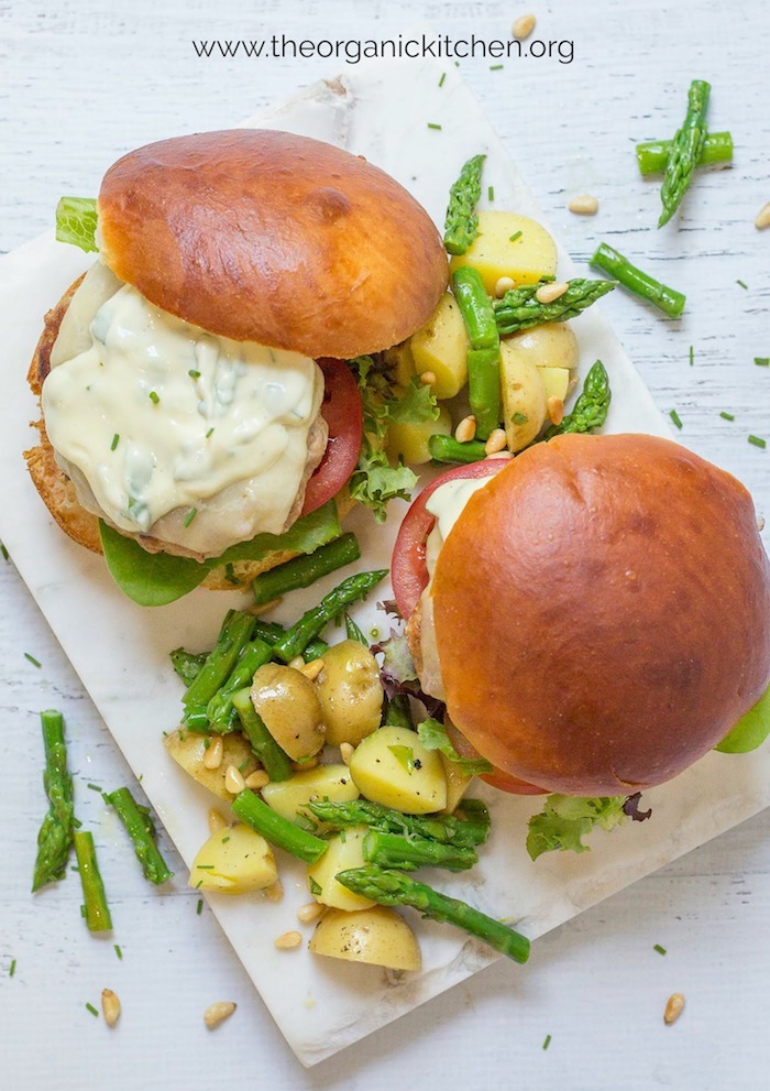 Jalapeño Turkey Burgers with Basil Mayo surrounded by potato salad with asparagus on a marble platter