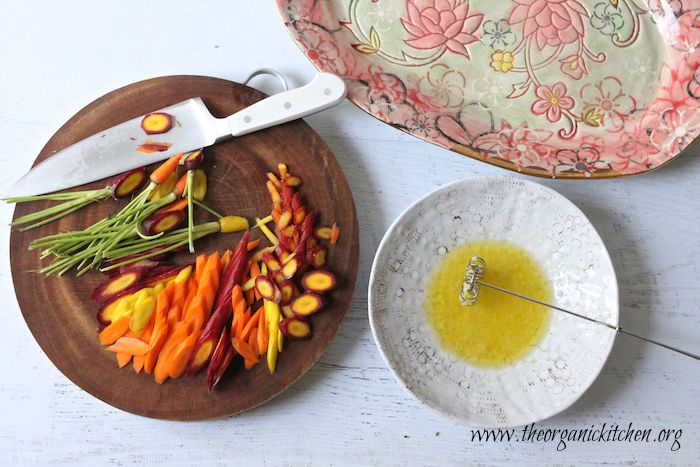 Ingredients for Linguini with Rainbow Carrots and Broccolini on a round cutting board