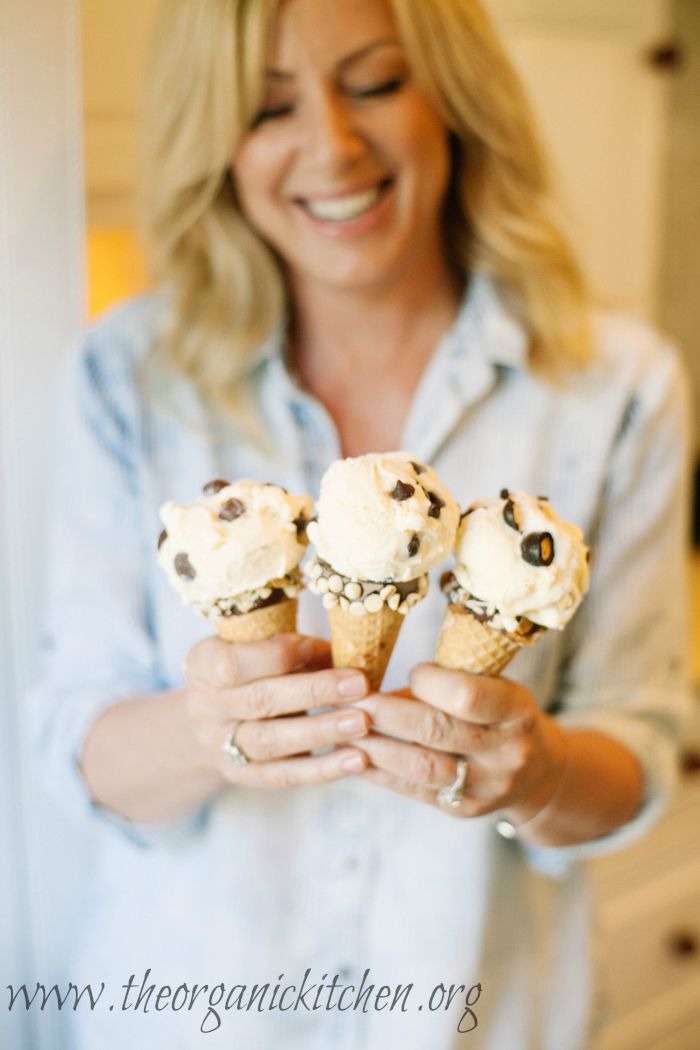 A smiling blond woman holding three ice cream cones