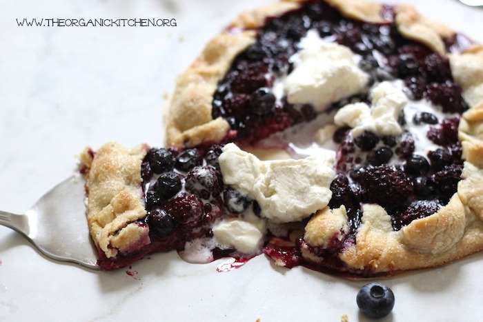 A Blackberry Walnut Galette with a slice being lifted by a silver spatula