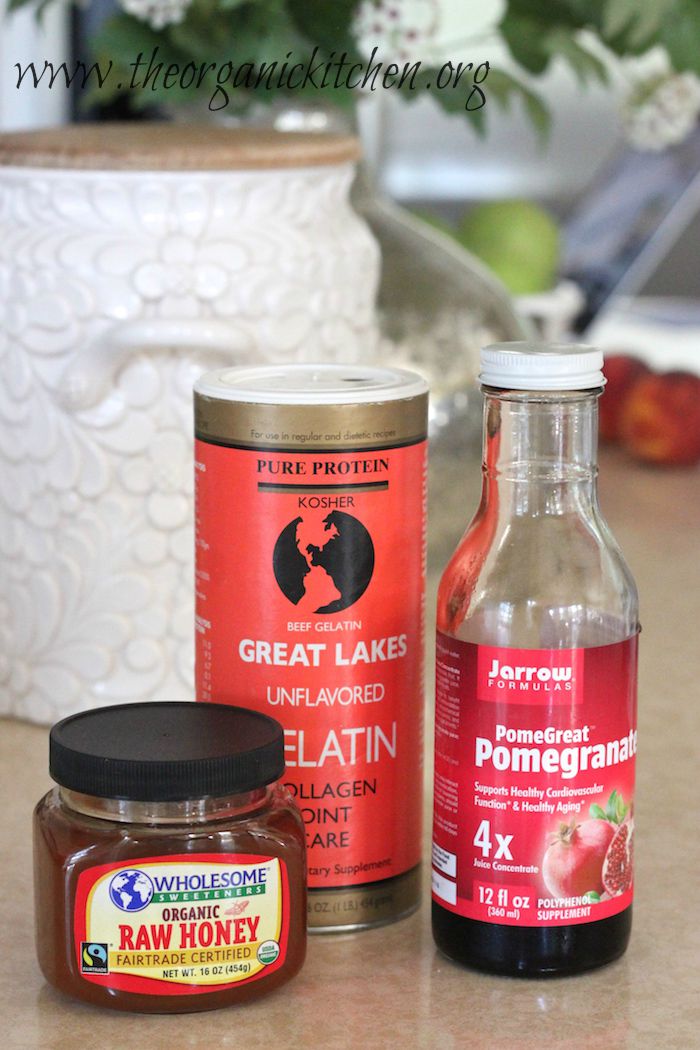 The ingredients for Pomegranate Gelatin Gummies: a jar of raw honey. a container of gelatin and pomegranate syrup