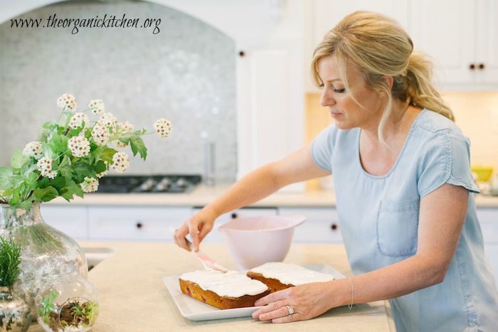 Lemon Raspberry Pound Cake A blonde woman ina blue shirt frosting a Lemon Raspberry Pound Cake