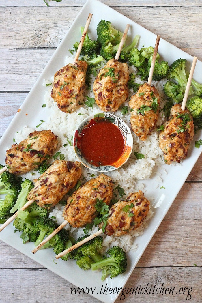 A white platter filled with Bacon Sriracha Chicken Skewers and Coconut Rice with Broccoli