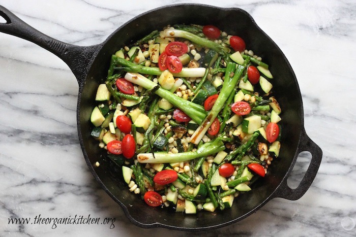 A black cast iron skillet filled with vegetables that will be used to make Grilled Skirt Steak and Veggies with Guacamole