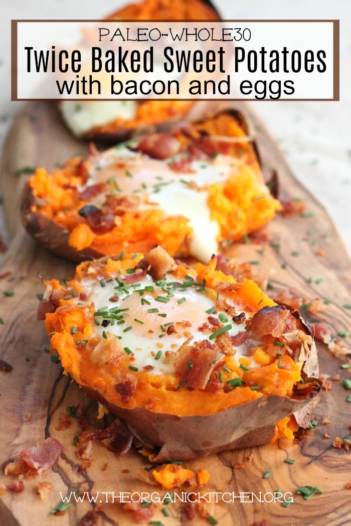 Three Twice Baked Sweet Potatoes with Bacon and Eggs set on a wooden platter and sprinkled with chopped chives