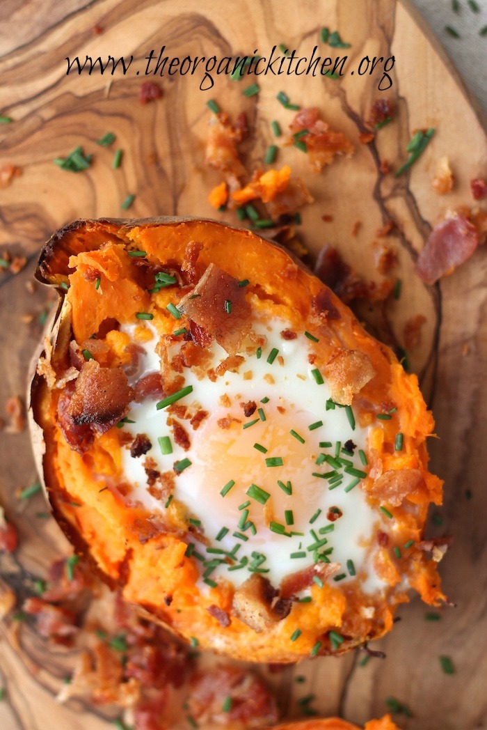 A close up of a single Twice Baked Sweet Potato with Bacon and Eggs on a wood platter