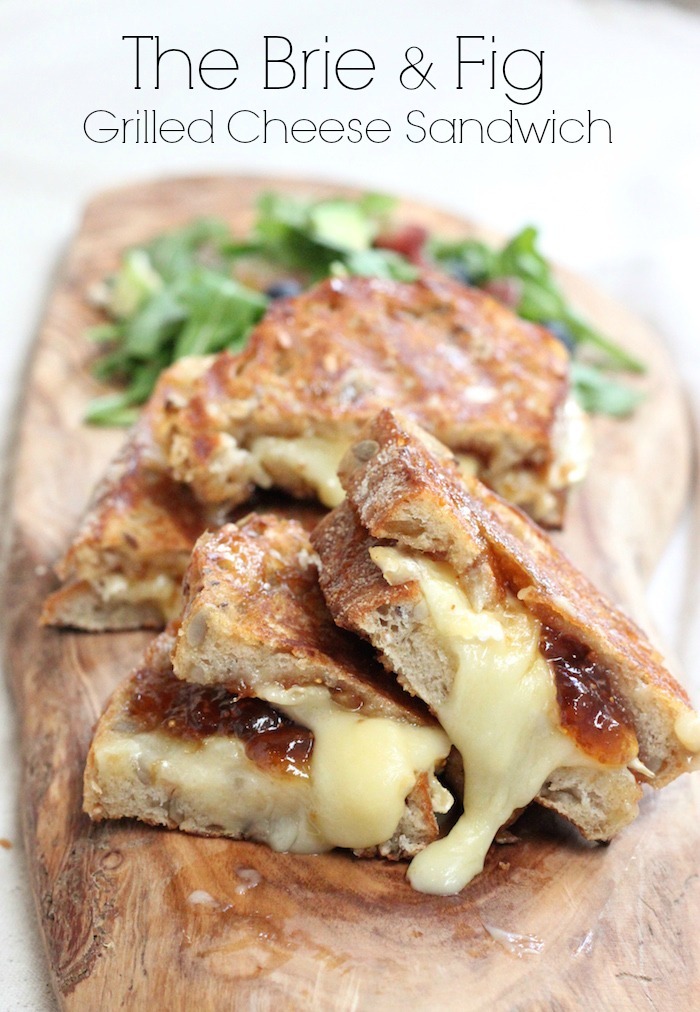 Brie and Fig Grilled Cheese on a wooden platter with greens