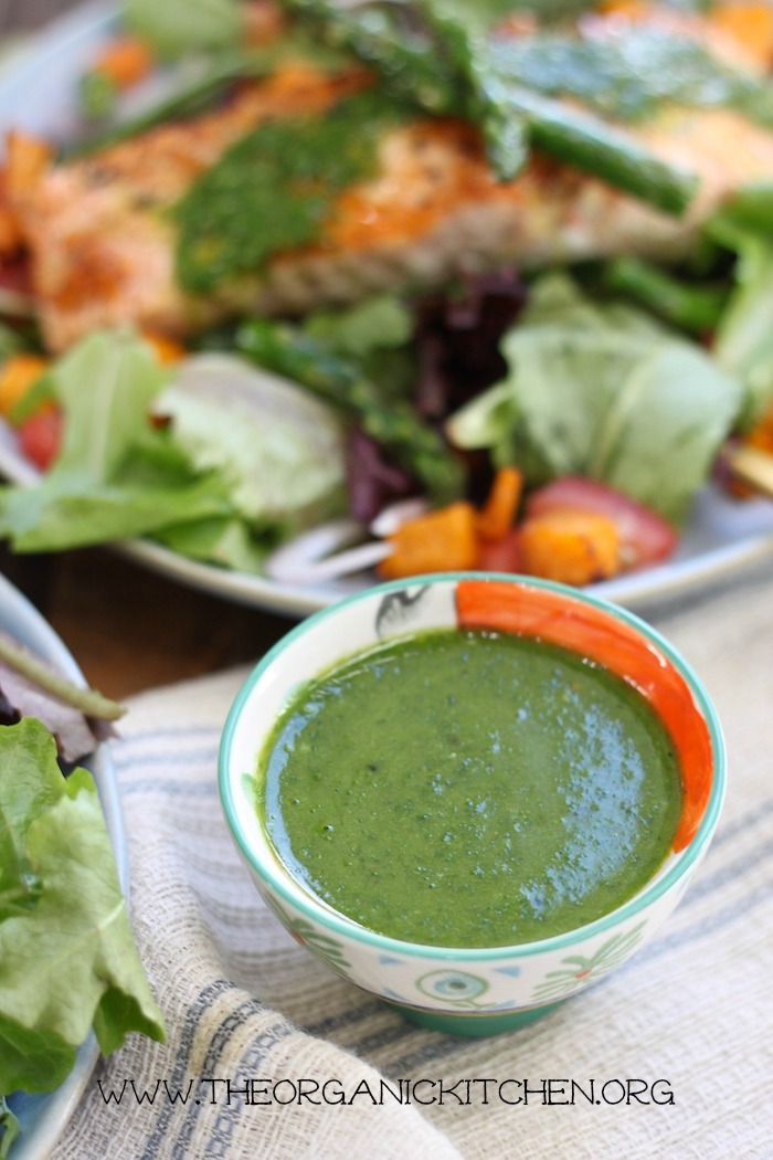 A small colorful bowl of pesto vinaigrette with salmon salad in the back ground