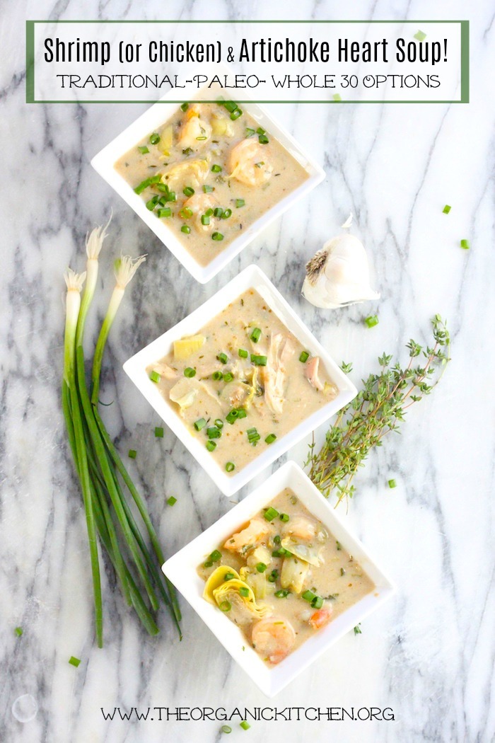 Three bowls of Shrimp (or Chicken) and Artichoke Soup on a marble surface surrounded by herbs and spring onions