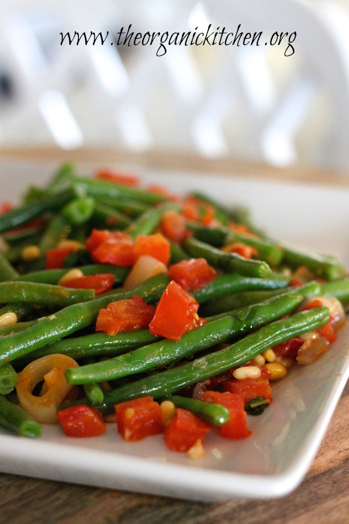 Grandma Julia's Green Beans: Green beans, tomatoes, pine nuts and onions on a white platter