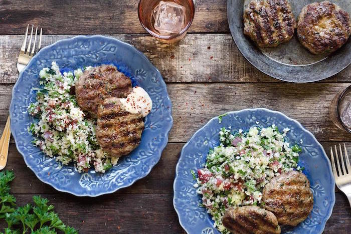 Two blue plates with Spiced Lamb Patties with Cauliflower Tabbouleh garnished with parsley