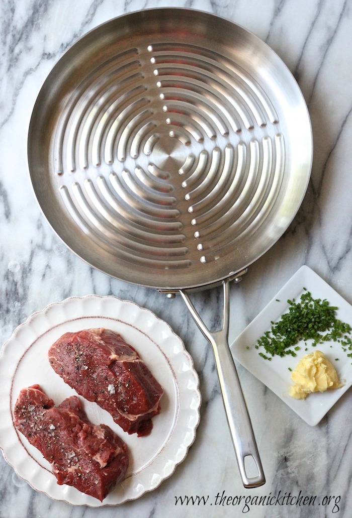 two steaks on a plate, a grill pan, butter and chives