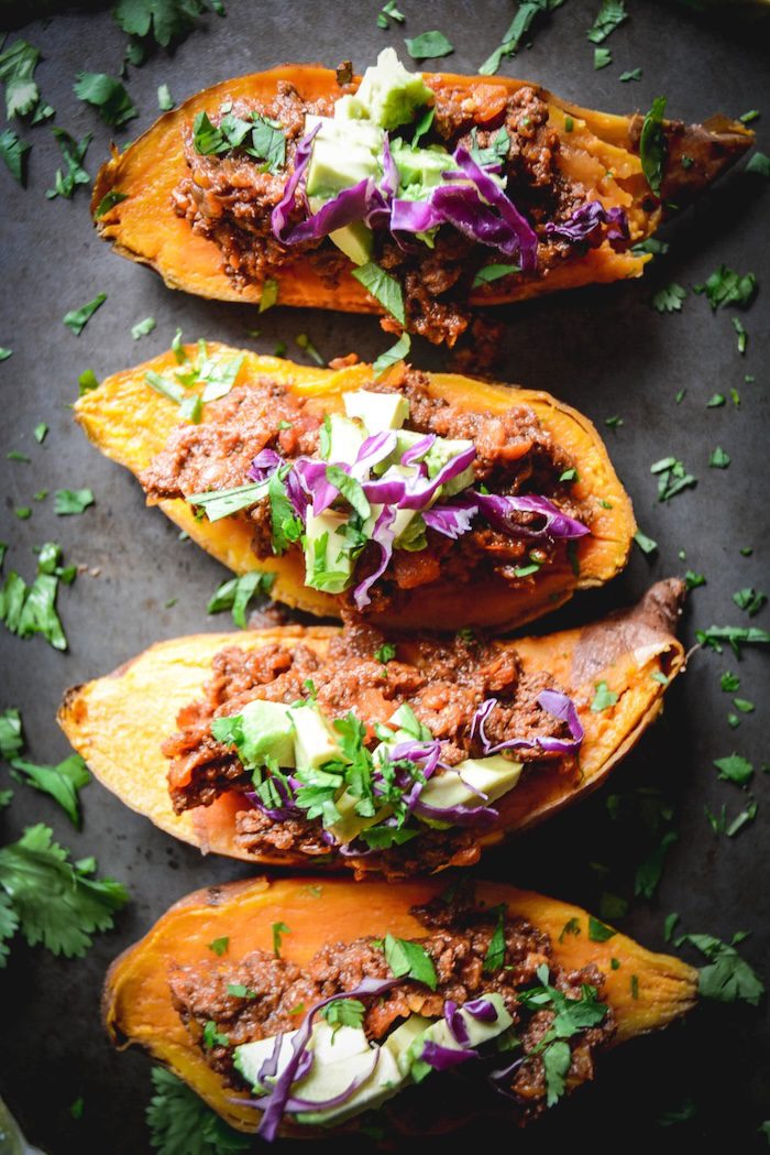 Chili Stuffed Sweet Potatoes garnished with herbs on black table