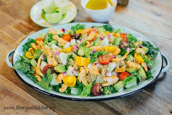 A Blackened Chicken and Quinoa Salad on green dish with lime wedges and salad dressing in background