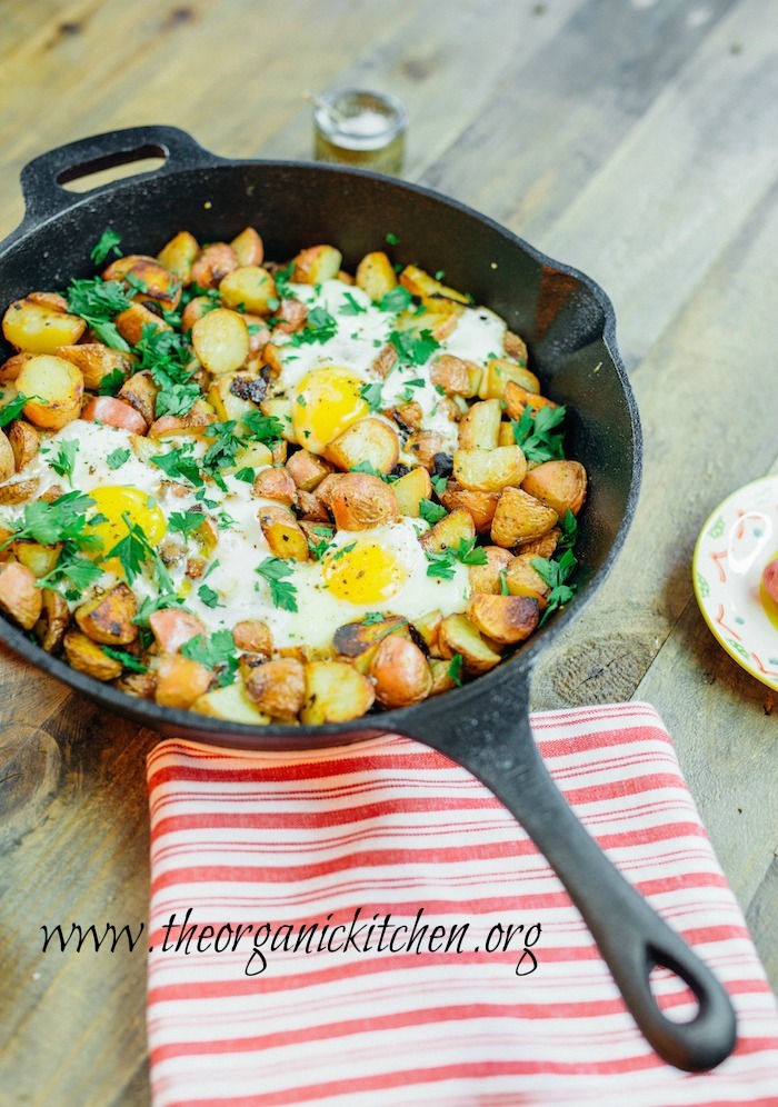 A black cast iron skillet filled with fried potatoes and eggs
