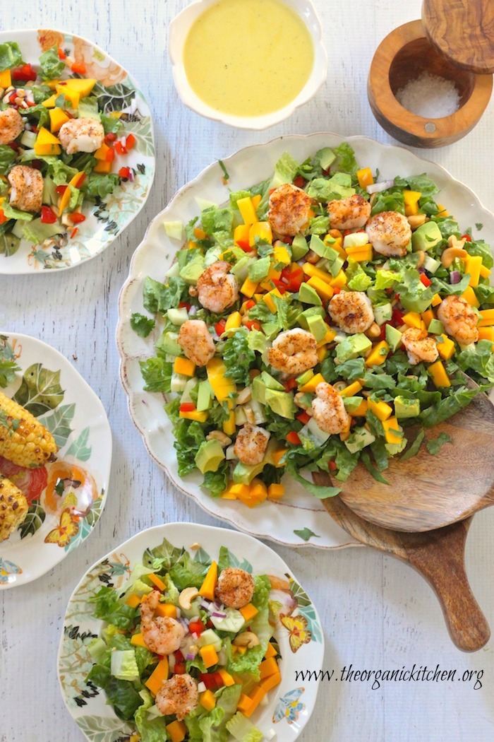 Four plates of Greens with Grilled Shrimp and Citrus Vinaigrette on white plates