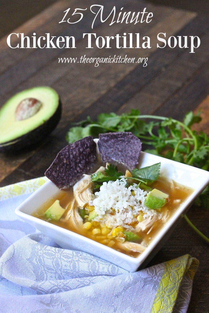15 Minute Chicken Tortilla Soup ina white bwol with blue tortilla chips and avocado