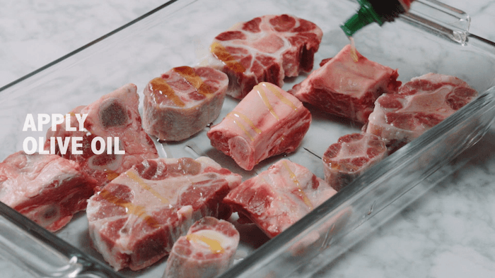 Beef bones drizzled with olive oil in a clear baking dish