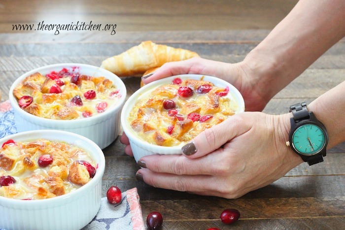 A woman's hands holding a white ramekin of Orange Cranberry Bread Pudding: Made with Croissants!