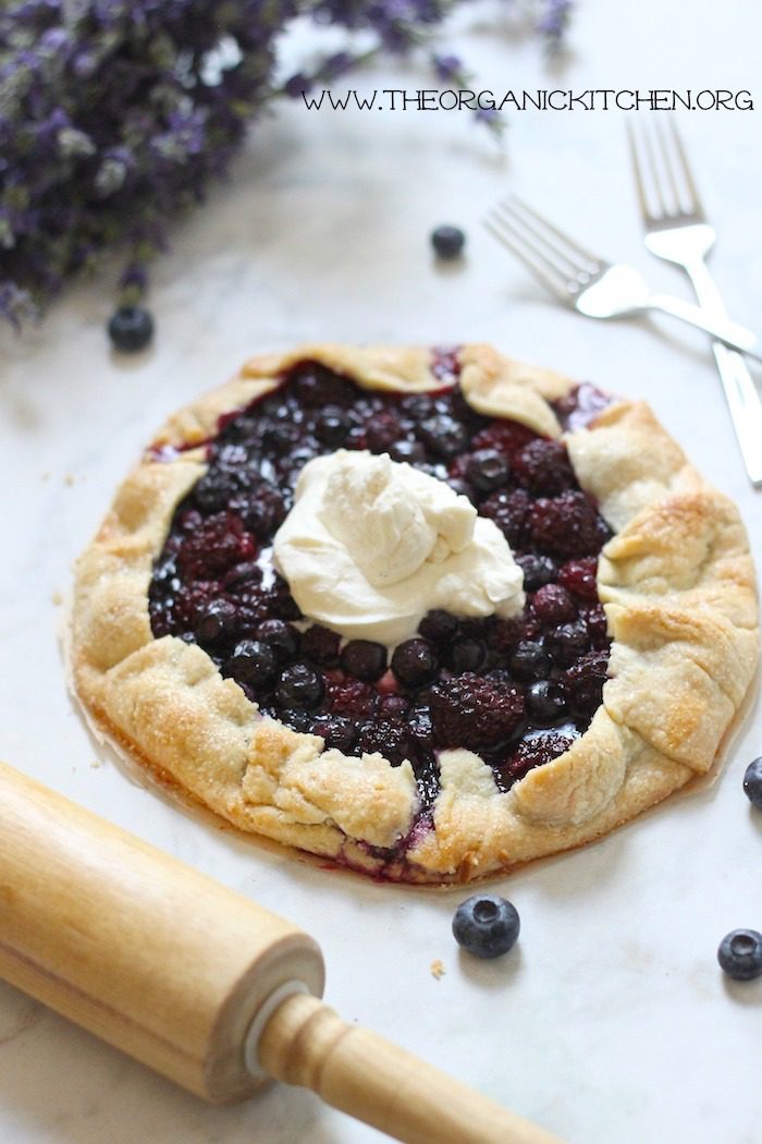 My Favorite Holiday Desserts A blackberry walnut galatte topped with whipped cream on a white surface with a rolling pin in the forground