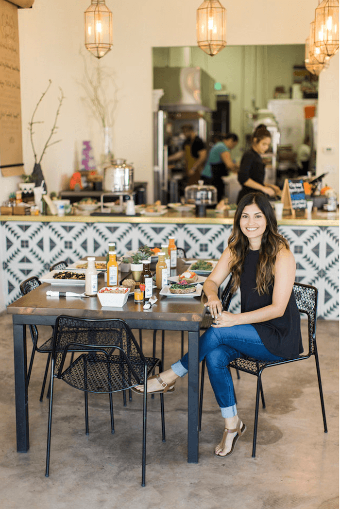 A pretty dark haired woman in jeans seated at a cafe table