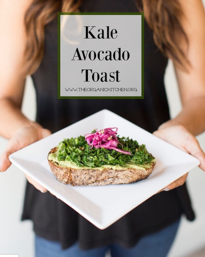 Kale Avocado Toast on white plate held by a woman in a black shrit